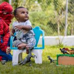 Kids enjoying playtime with dinosaur toys and costumes in a sunny garden.